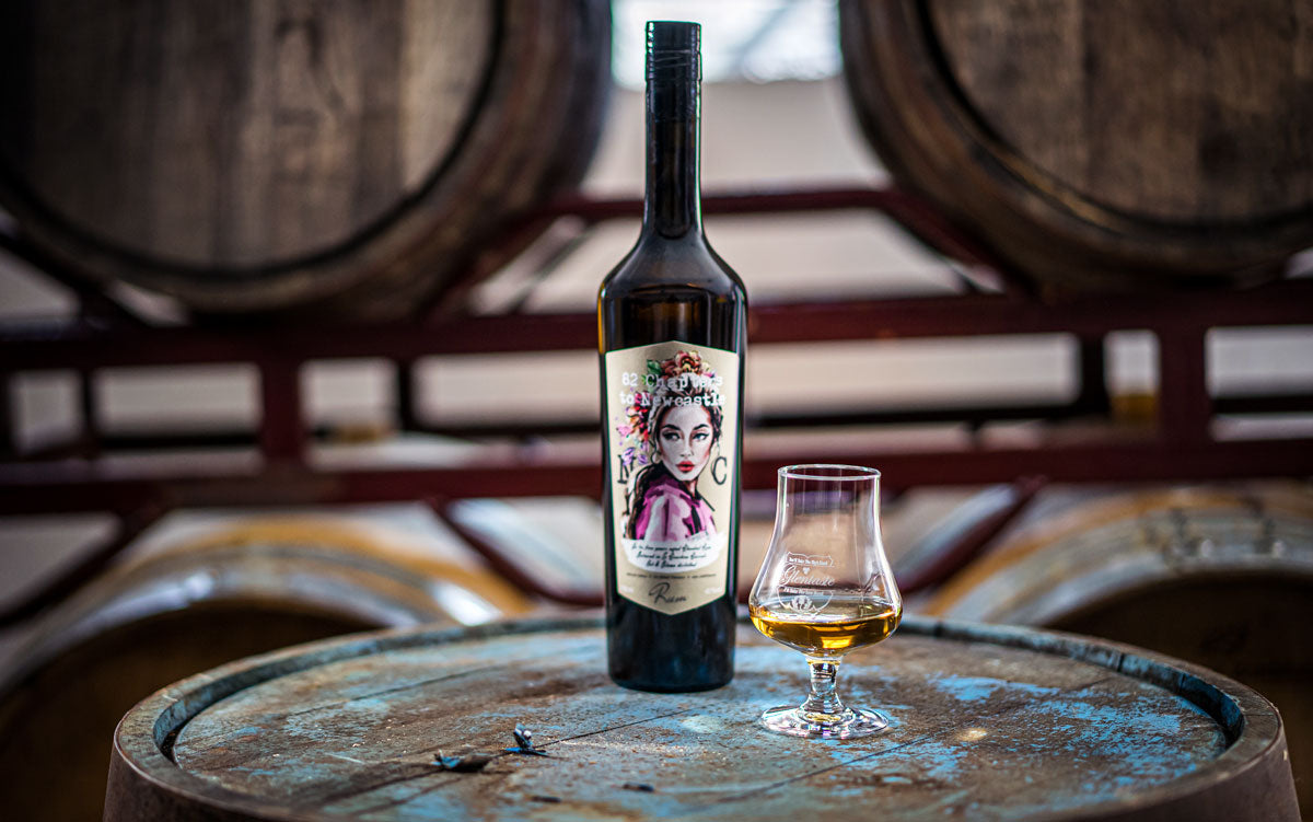Rumflasche The Beauty auf Fass mit Glas Rum davor